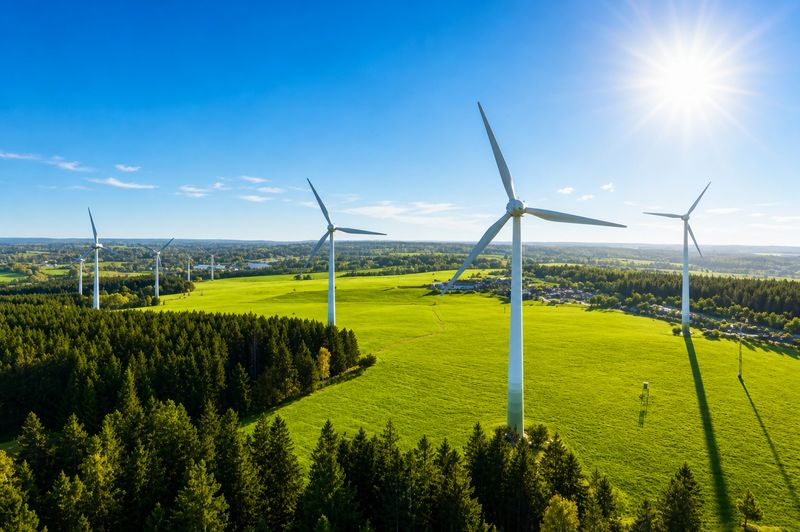 Onshore wind farm above green fields and forest